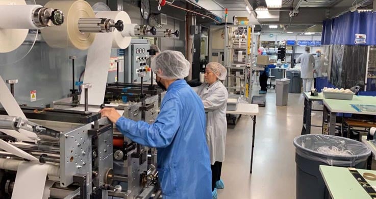 clean room precision converting on a multi station rotary die cutting machine with several technicians in clean room apparel at Boyd