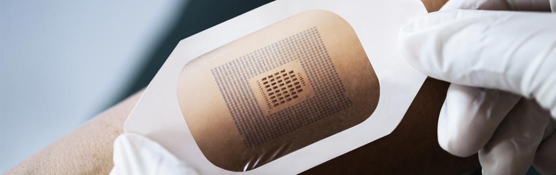 A medical wearable patch being applied to an arm The-Rail-Industry-and-Boyd-Solutions